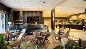 Um lobby moderno de hotel com área de bar, espaços para sentar e balcão de recepção.