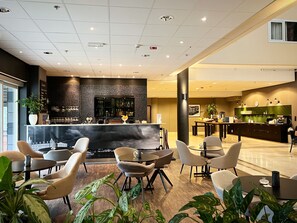 A modern hotel lobby with a bar area, seating arrangements, and a reception desk. - Hoom Park (Solna)