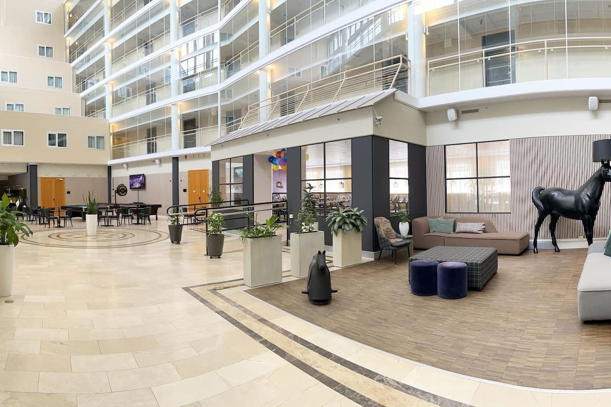 A hotel lobby with a reception desk, seating areas, and a large black horse statue.