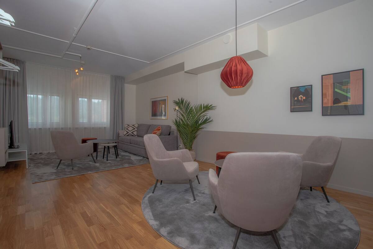 A modern living room with a sofa, two armchairs, a coffee table, and a potted plant.