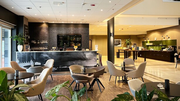 Un moderno vestíbulo de hotel con zona de bar, asientos y mostrador de recepción.