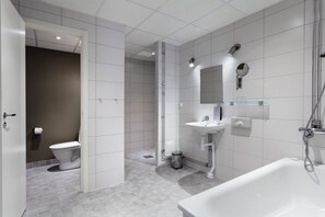 A modern bathroom with a toilet, shower, sink, and bathtub. - Hoom Park (Solna)