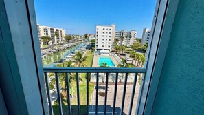 A view of a marina with boats, a swimming pool, and surrounding buildings. - Casa Marina 424 - Dockside Living (Fort Myers Beach)