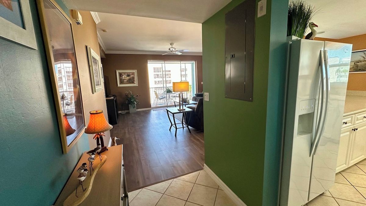 Una cocina con refrigerador, un comedor con sillas y vista al exterior.