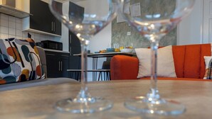Moderni keittiö, jossa on tummat kaapit, ruokapöytä ja punainen sohva, jossa on kuvioidut koristetyynyt.