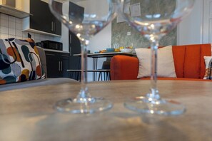 A modern kitchen with dark cabinets, a dining table, and a red sofa with patterned cushions. - Modern 1-Bed Flat – Hamilton House, Bromley-by-Bow (London)