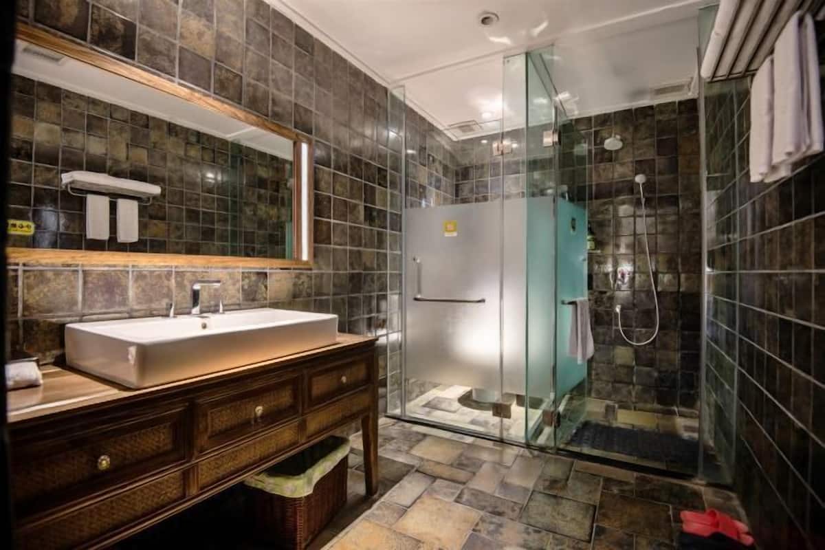 A bathroom with a glass-enclosed shower, a sink with a mirror, and a vanity with drawers.