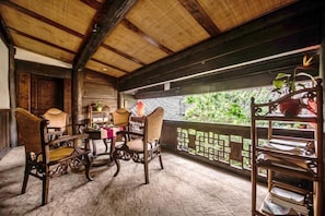 A traditional wooden room with a thatched roof, a wooden table with chairs, and a view through a lattice window. - Langzhong Lijia Quadrangle Inn (Langzhong)