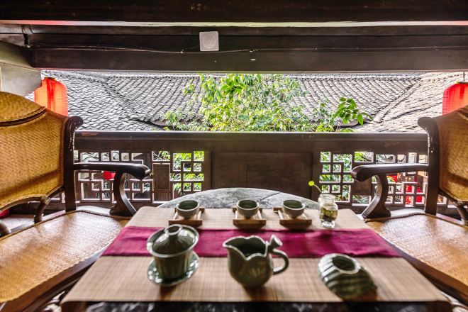 A traditional tea setting with a table, chairs, and tea utensils.