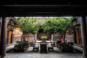 An indoor courtyard with traditional wooden architecture, potted plants, and seating arrangements. - Langzhong Lijia Quadrangle Inn (Langzhong)