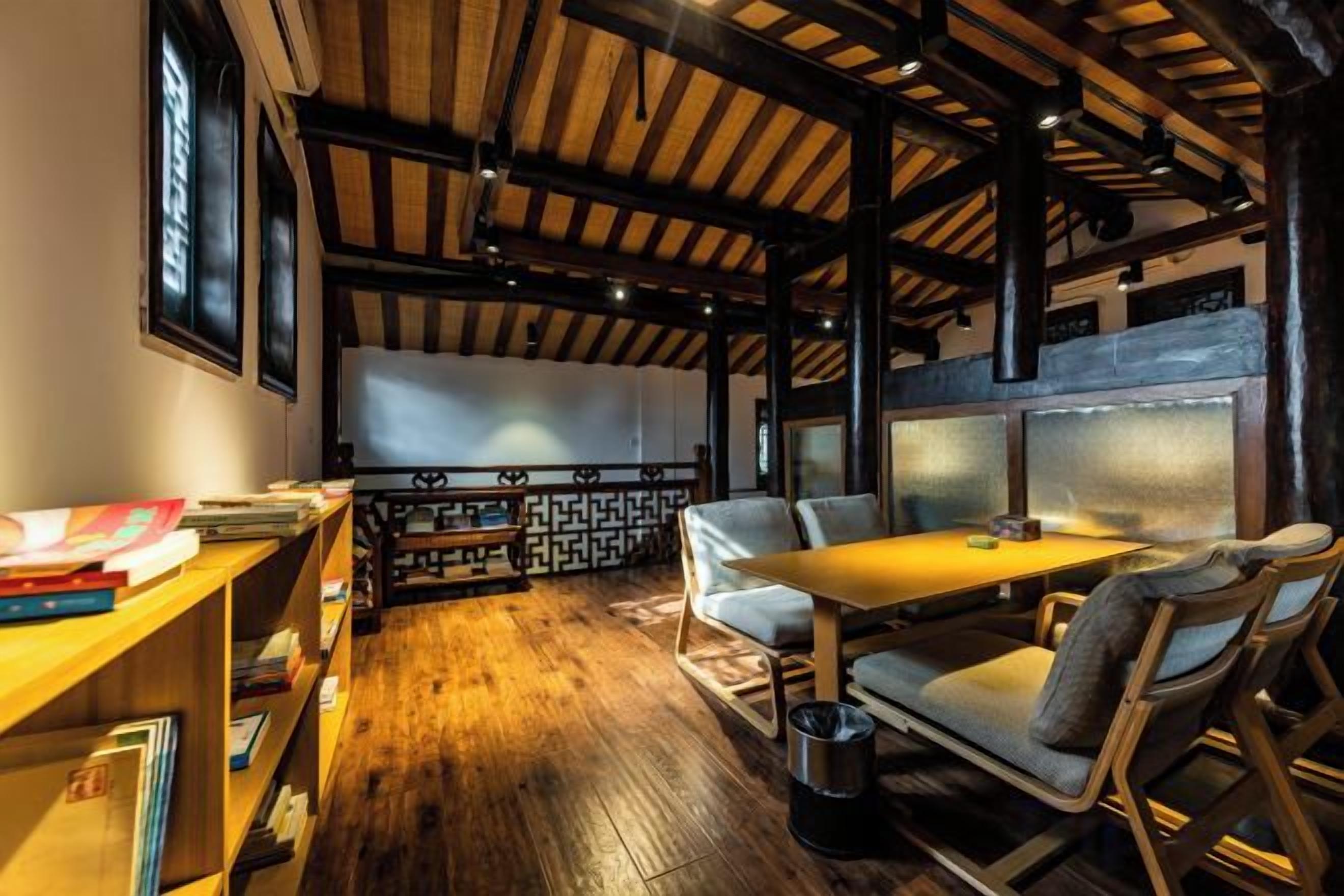 Una habitación acogedora con techo de madera, un sofá, una mesa y una estantería.