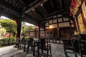 A traditional wooden structure with tables and chairs, likely a restaurant or tea house, with a view of the surrounding garden. - Langzhong Lijia Quadrangle Inn (Langzhong)