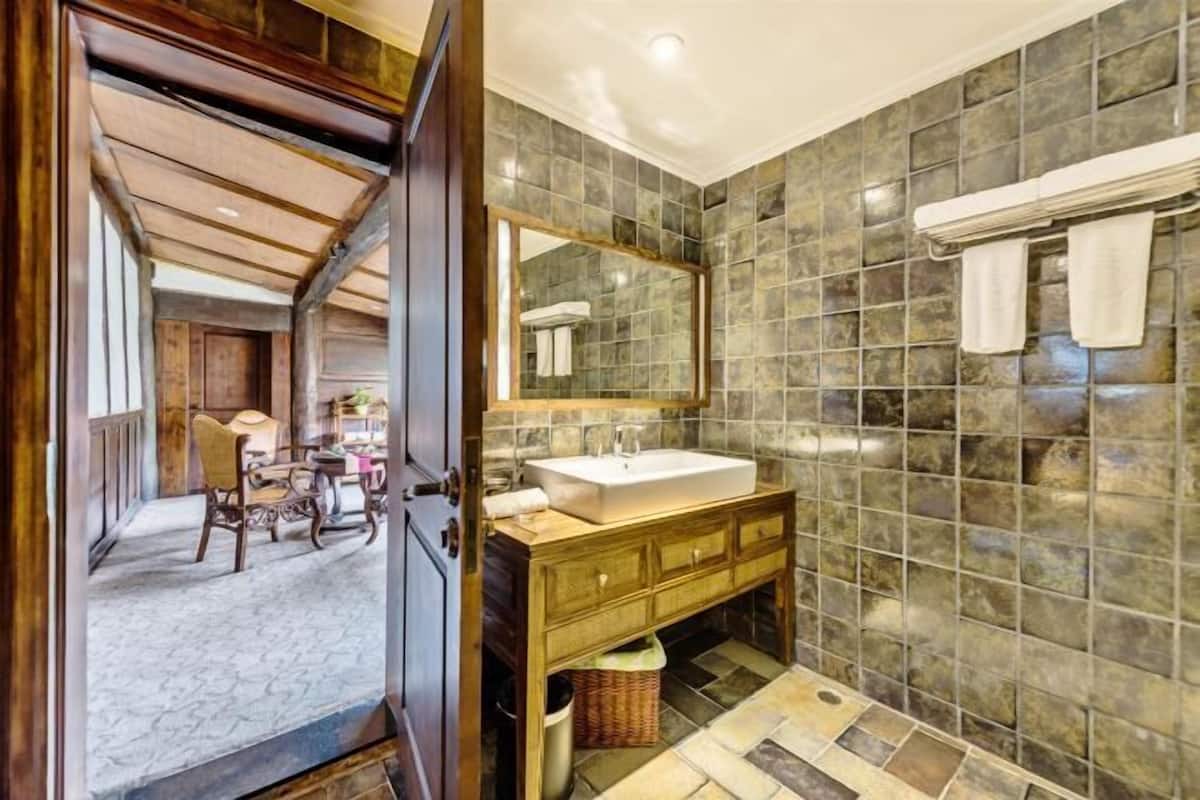 A bathroom with a large mirror, a sink, and a tiled wall.