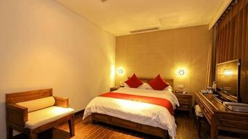 Een hotelkamer met een groot bed, nachtkastjes, een houten bankje en een spiegel.