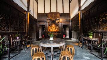 A traditional interior with a round table surrounded by wooden stools, a central decorative element, and patterned walls.