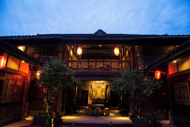 A traditional building with a balcony, wooden doors, and lanterns.