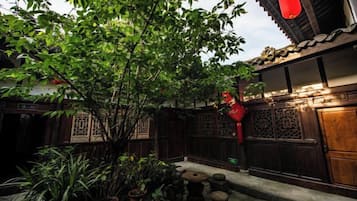 A traditional courtyard with a tree, potted plants, and a wooden gate.