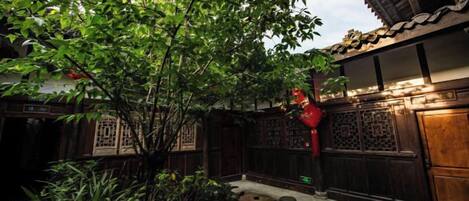 Un patio tradicional con un árbol, plantas en macetas y una puerta de madera.