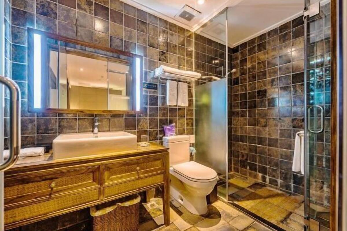 A bathroom with a sink, mirror, toilet, and shower.