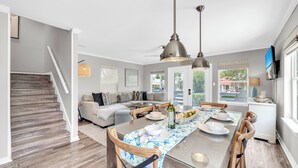 Une cuisine moderne avec une table à manger, des chaises et des luminaires suspendus.
