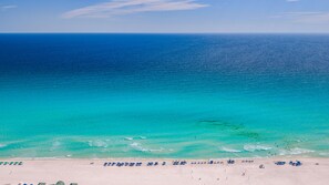 Ein Strand mit klarem türkisblauem Wasser, sandigem Ufer und Sonnenschirmen.