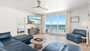 Una sala de estar moderna con un ventanal grande, un ventilador de techo y vistas a la playa.