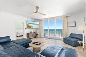 A modern living room with a large window, a ceiling fan, and a view of the beach. - Tidewater 201•Remodeled•Beachfront•Pools&Hot Tubs •Beach Gear•Fitness Center (Panama City Beach)