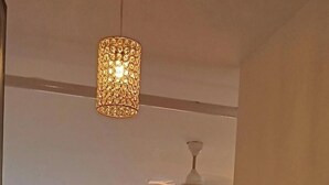 Een hotelkamer met een bed, een plafondventilator, een hanglamp en uitzicht door het raam.