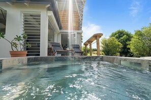 A pool area with a view of a building, a potted plant, and a wooden structure. - Appartement Mango Bliss (Sainte-Luce)