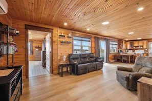 A wooden interior with a sofa, a dining table, and a kitchen area.