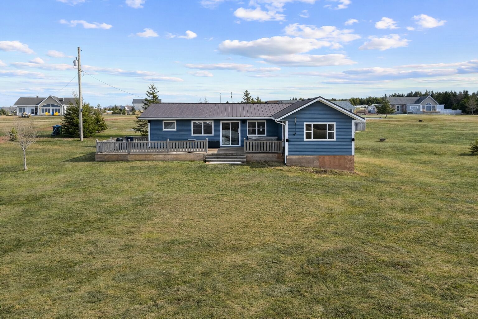 A single-story house with a front porch, a small deck, and a grassy yard.