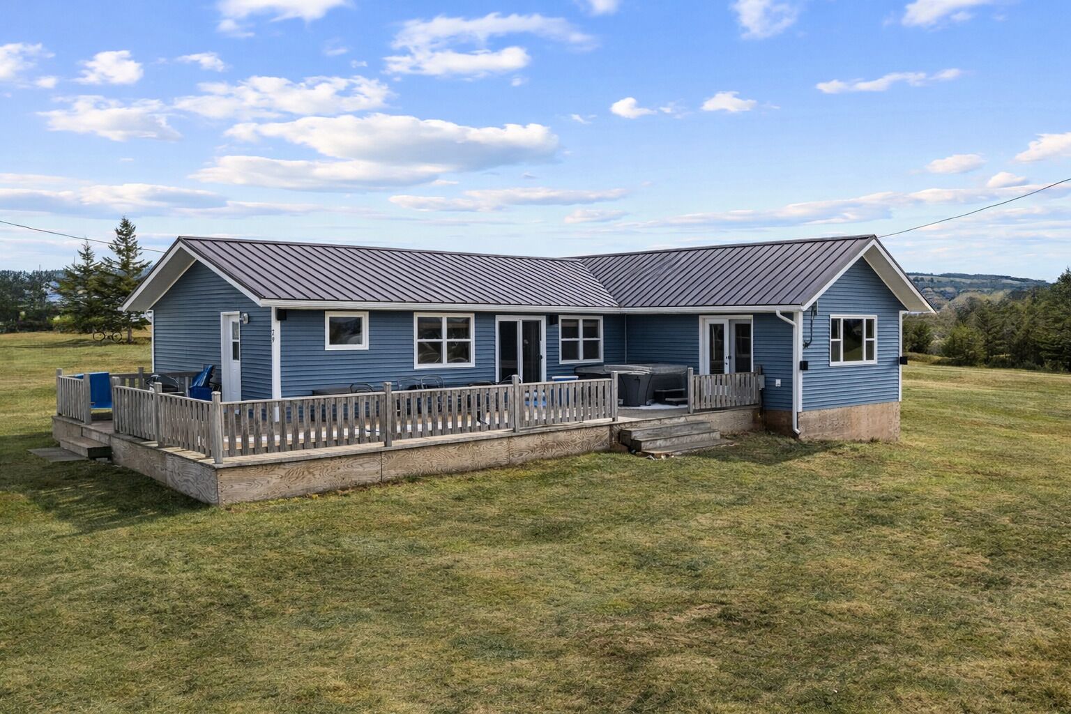 A two-story house with a porch, a fenced deck, and a grassy yard.