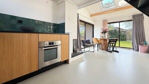 Eine moderne Küche mit Holzschränken, einem eingebauten Backofen und einer digitalen Uhr.