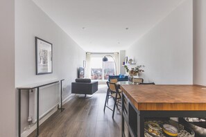 A modern kitchen with a wooden table, chairs, and a radiator. - Stylish Wimbledon Flat with Balcony (London)