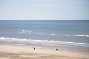 A beach with a wide sandy shore, gentle waves, and a clear sky. - Luxury Seaview Apartment for 4 (Egmond aan Zee)