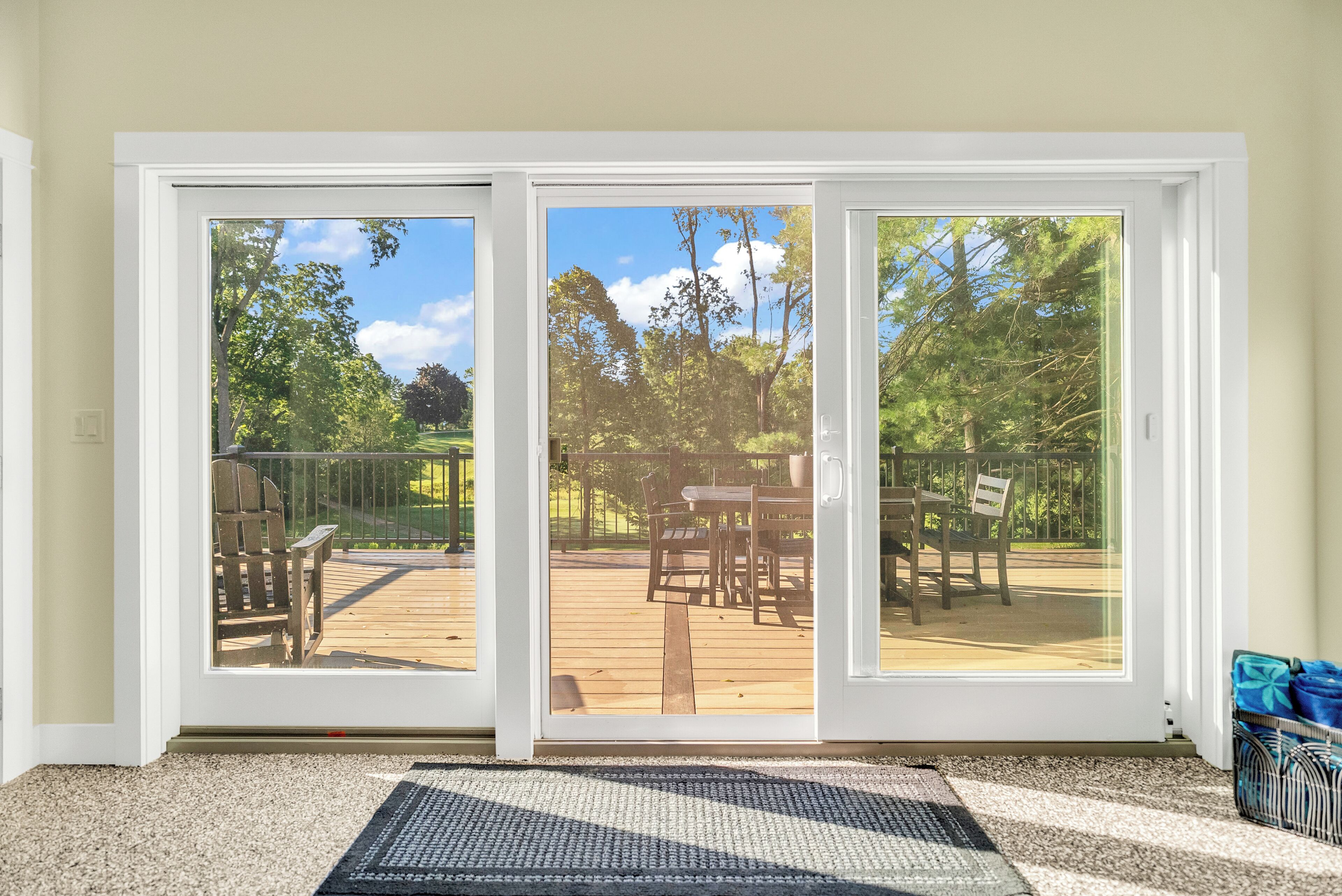 Eine Glastür führt zu einer Terrassenanlage mit Tisch und Stühlen.