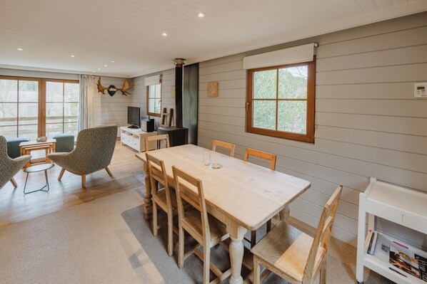 A dining area with a wooden table and chairs, a television, and a bookshelf.