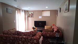A living room with a sofa set, a television, and a small table with a vase.