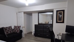 A bedroom with a bed, a desk, a chair, a dresser, and a mirror.