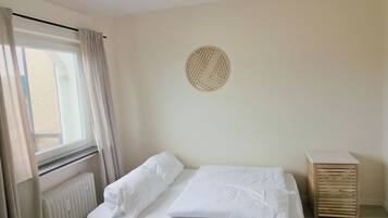 Ein Schlafzimmer mit Bett, Heizkörper, einem fenster mit Vorhängen und einem Wanddekor.