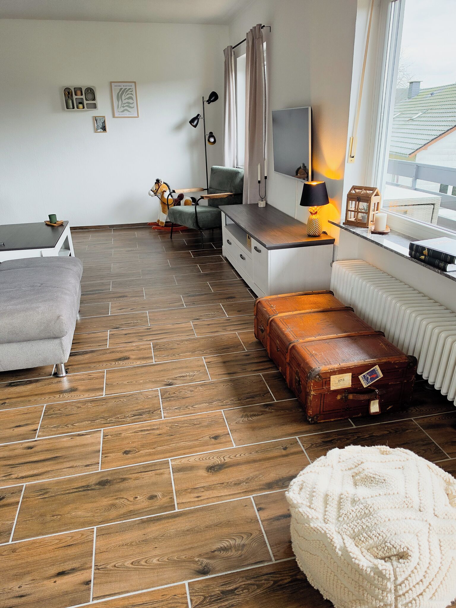 A modern living room with a sofa, a small table, a lamp, a suitcase, and a radiator.