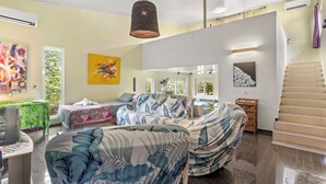 Habitación de hotel moderna con una cama grande, un escritorio y una silla. Se ve una ventana con vistas a zonas verdes, un cuadro en la pared y una escalera.