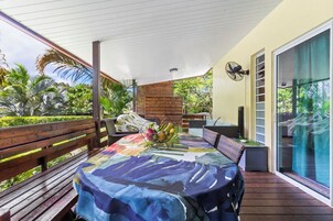 A covered outdoor patio with a table, chairs, and a fan.