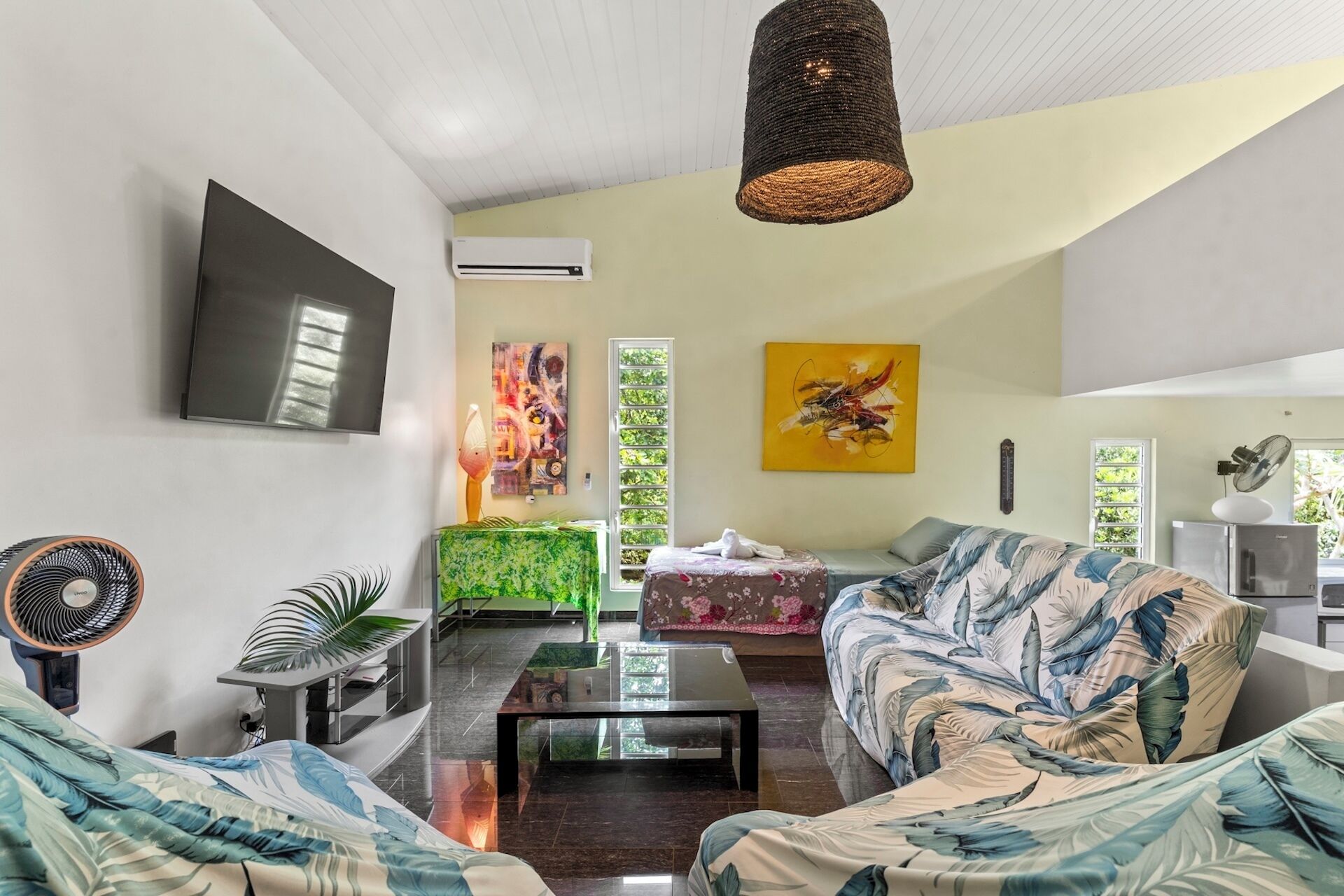 A living room with a sofa, a coffee table, a TV, and artwork on the walls.