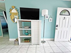 A room with a television on a stand, a white door with the number 3, and a floor lamp. - Surf & Sand - 1 bedroom Suite (Cape Canaveral)