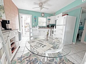 A kitchen with a dining table, white cabinets, a refrigerator, and a ceiling fan. - Surf & Sand - 1 bedroom Suite (Cape Canaveral)