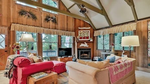 Una habitación acogedora con techo de madera, chimenea y sofá rojo.