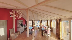 A spacious room with a kitchen, dining area, and large windows offering views.
