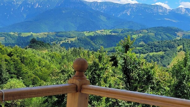 A mountain landscape with a wooden railing in the foreground.