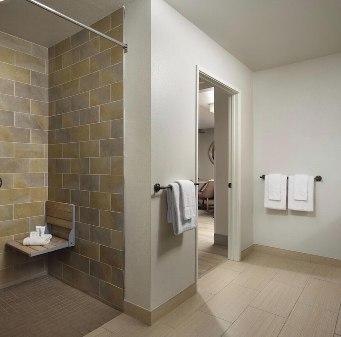 Een badkamer met een douche, een handdoekhouder en een klein plankje met handdoeken.